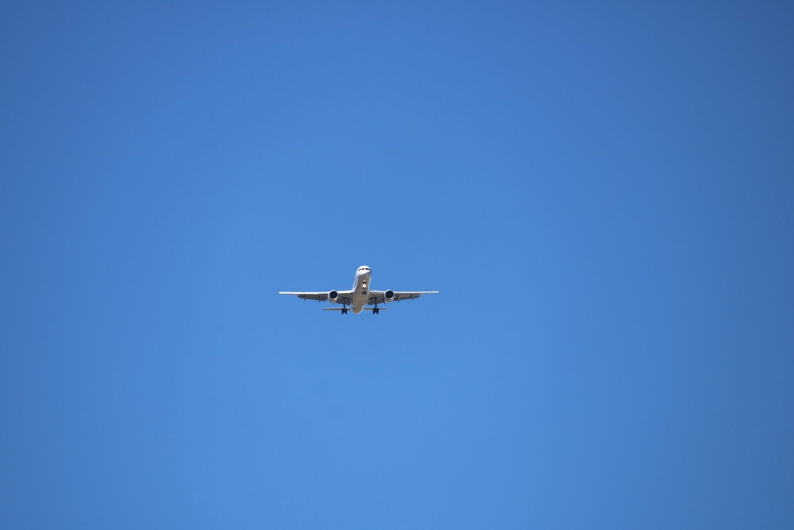 Low angle photography of gray airplane under blue sky at daytime